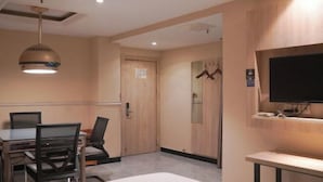 Habitación de hotel con cama, escritorio con silla, televisor montado en la pared y lámpara en el techo.