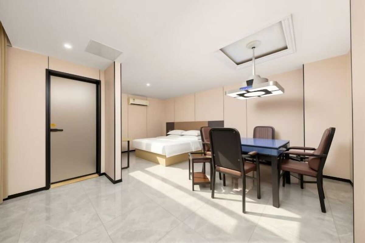 Una habitación de hotel con cama, escritorio con sillas, mesa y lámpara de techo.