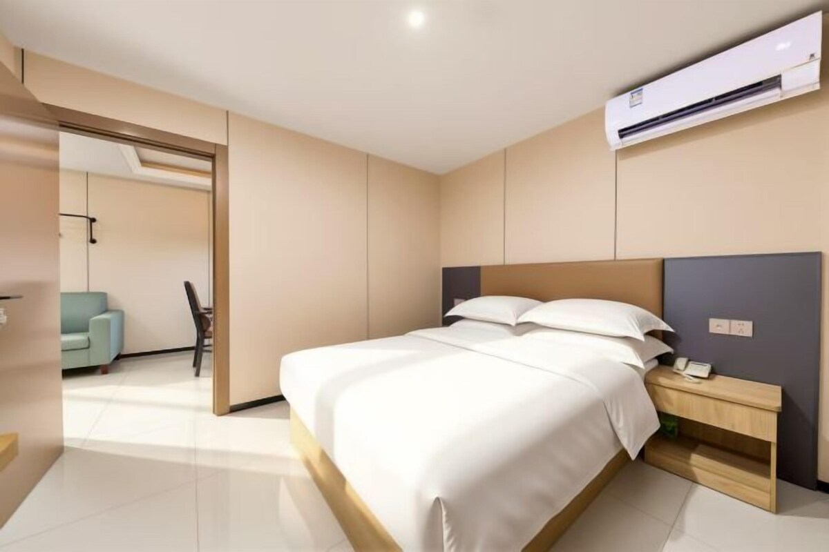 Una habitación de hotel moderna con una cama grande, una mesita de noche y un equipo de aire acondicionado.