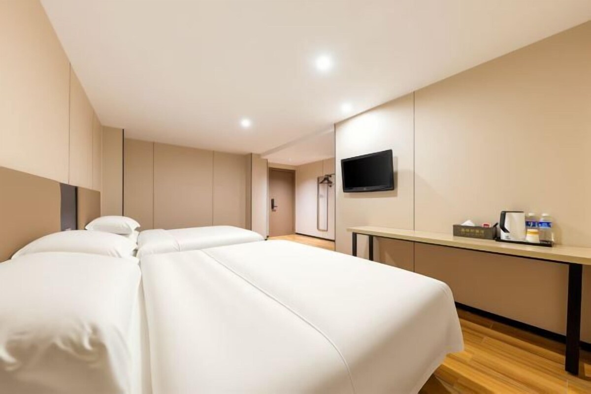 Una habitación de hotel con cama, escritorio, televisor y espejo.
