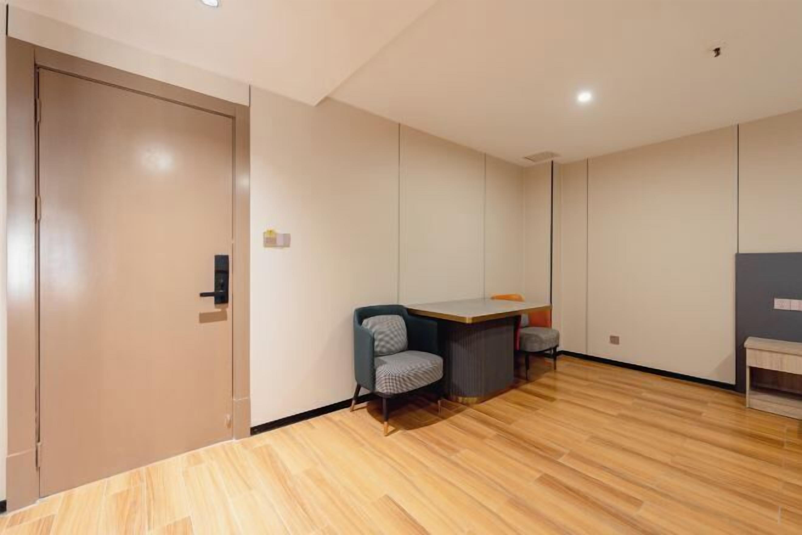 Una habitación con suelo de madera, un escritorio, una silla y un armario.