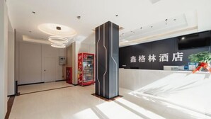 Zona de recepción de un hotel con diseño moderno, que incluye un mostrador de recepción, una máquina expendedora y un pilar grande.