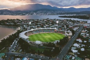 An aerial view of a stadium with a surrounding residential area and mountains in the background.
