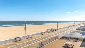 Een uitzicht op het strand met een houten pier, banken en een picknicktafel.