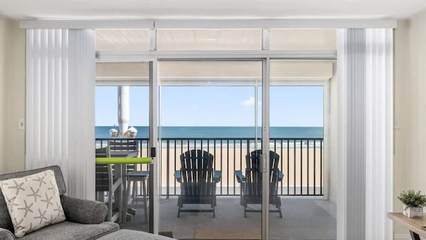 Een balkon met uitzicht op het strand, een tafel, stoelen en een bank.