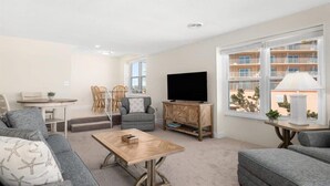 Een moderne woonkamer met een bank, fauteuil, televisie en een eethoek.