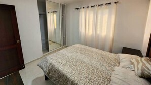 A bedroom with a bed, a wardrobe, and a mirror. - Charming 3-bed Apartment 2 Bano Aire Acondicionado (Santo Domingo Oeste)