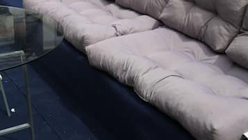 Ein Ecksofa mit einem Glastisch in einem Raum mit dunklem Boden.