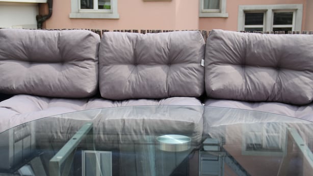 A glass-top table with a cushioned sofa in the background. - Stay2Night Hostel (Zürich)