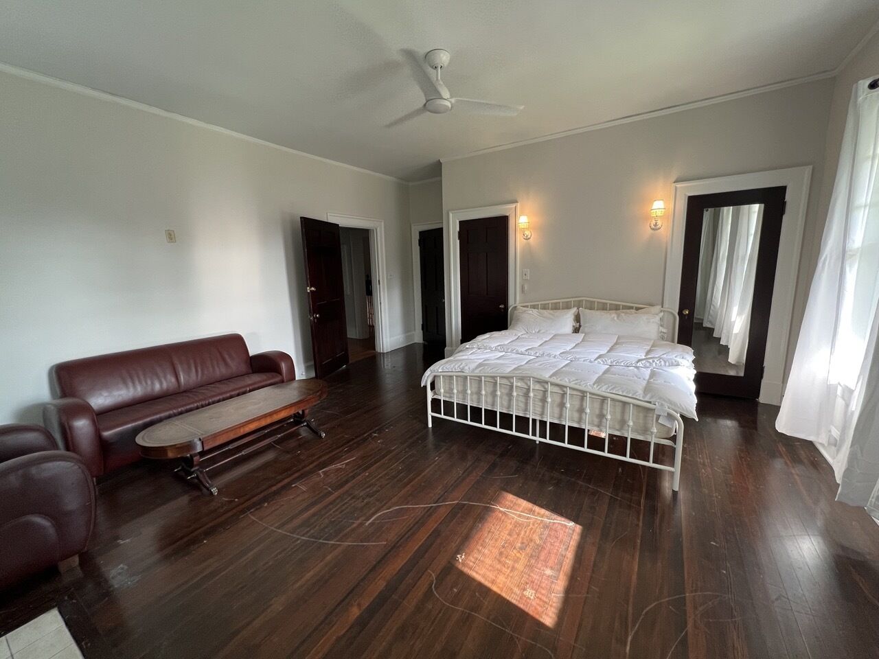 A bedroom with a large bed, a sofa, and a ceiling fan.