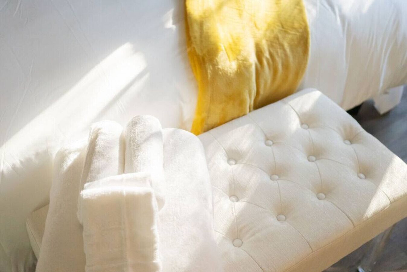 A bed with white bedding and a tufted headboard.
