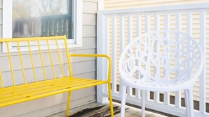 A yellow bench and a white chair on a porch with a white railing. - Candy Land- Downtown ILM (Wilmington)