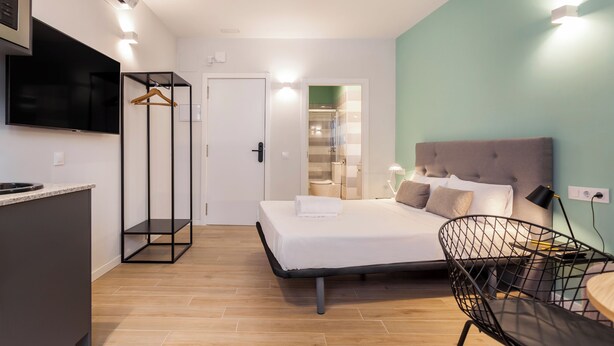 Una habitación de hotel moderna con cama, escritorio, silla y televisor.