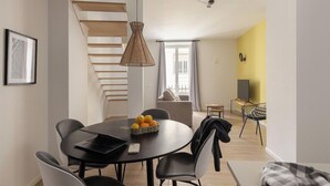 Una sala moderna con comedor, escalera y pared de acento amarilla.