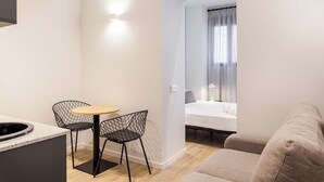 Un espacio habitable compacto con kitchenette, una zona de comedor con dos sillas, una cama y un sofá.