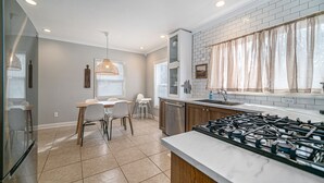 A modern kitchen with a gas stove, white cabinets, and a dining area with chairs and a table. - Updated Modern & Spacious 2 bed Apartment Near Everything! (Jackson)