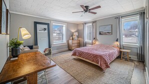 A bedroom with a bed, a desk, a chair, a ceiling fan, and a window with curtains. - Updated Modern & Spacious 2 bed Apartment Near Everything! (Jackson)