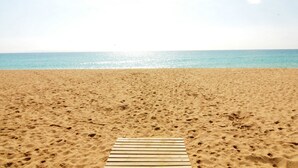 A sandy beach with a wooden boardwalk leading to the water.