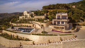 Une villa de luxe dotée d’une piscine, de murs en pierre et offrant une vue sur le paysage environnant.