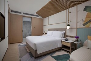 Une chambre d’hôtel moderne avec un grand lit, une table de chevet et une petite table de chevet avec une lampe.