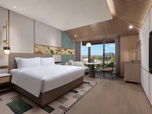 Ein modernes Hotelzimmer mit einem großen Bett, einem Essbereich und Blick auf die Stadt.
