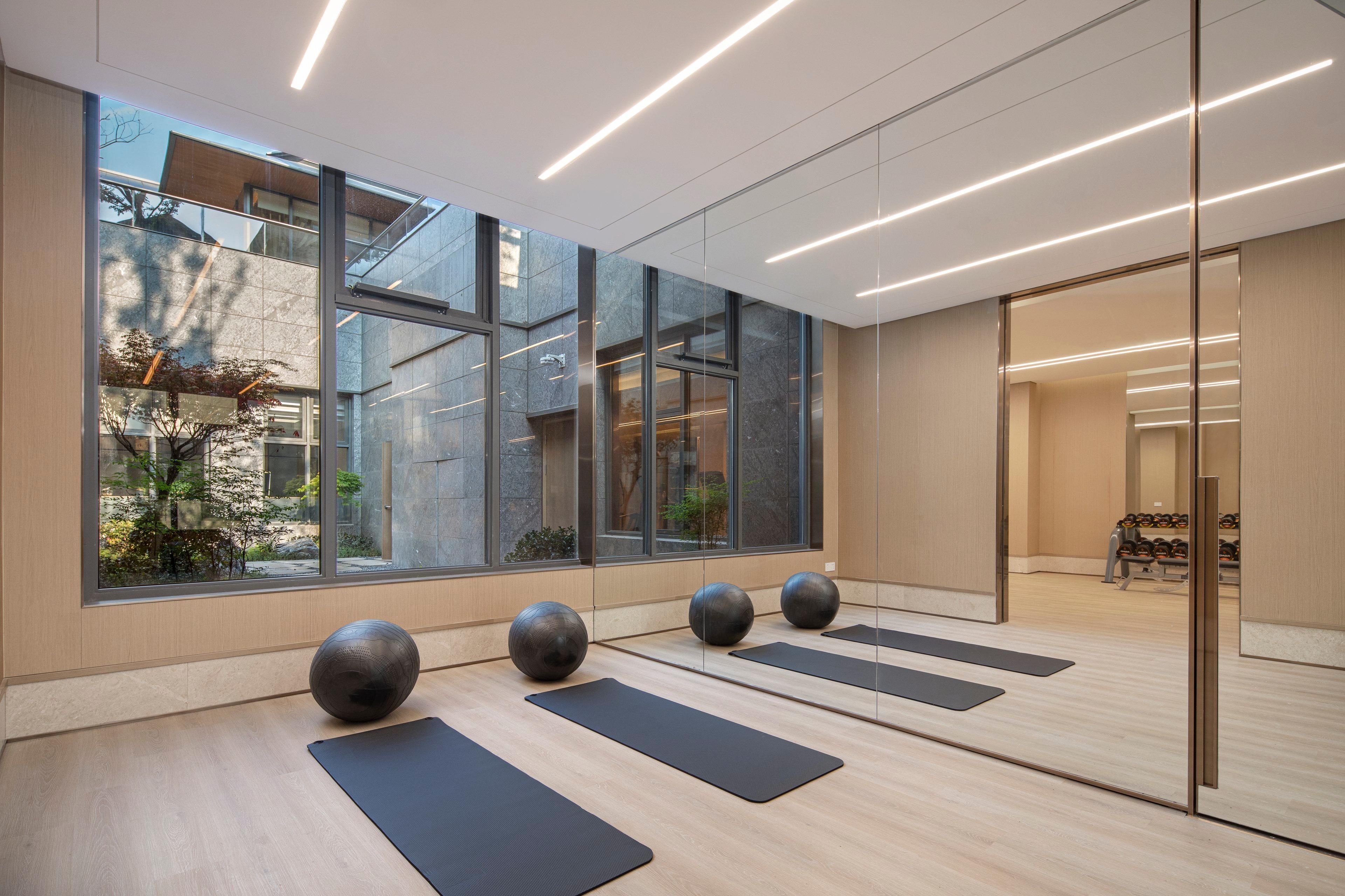 A modern gym with large windows, exercise mats, and exercise balls.