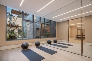 Un gimnasio moderno con amplios ventanales, colchonetas y pelotas de ejercicio.