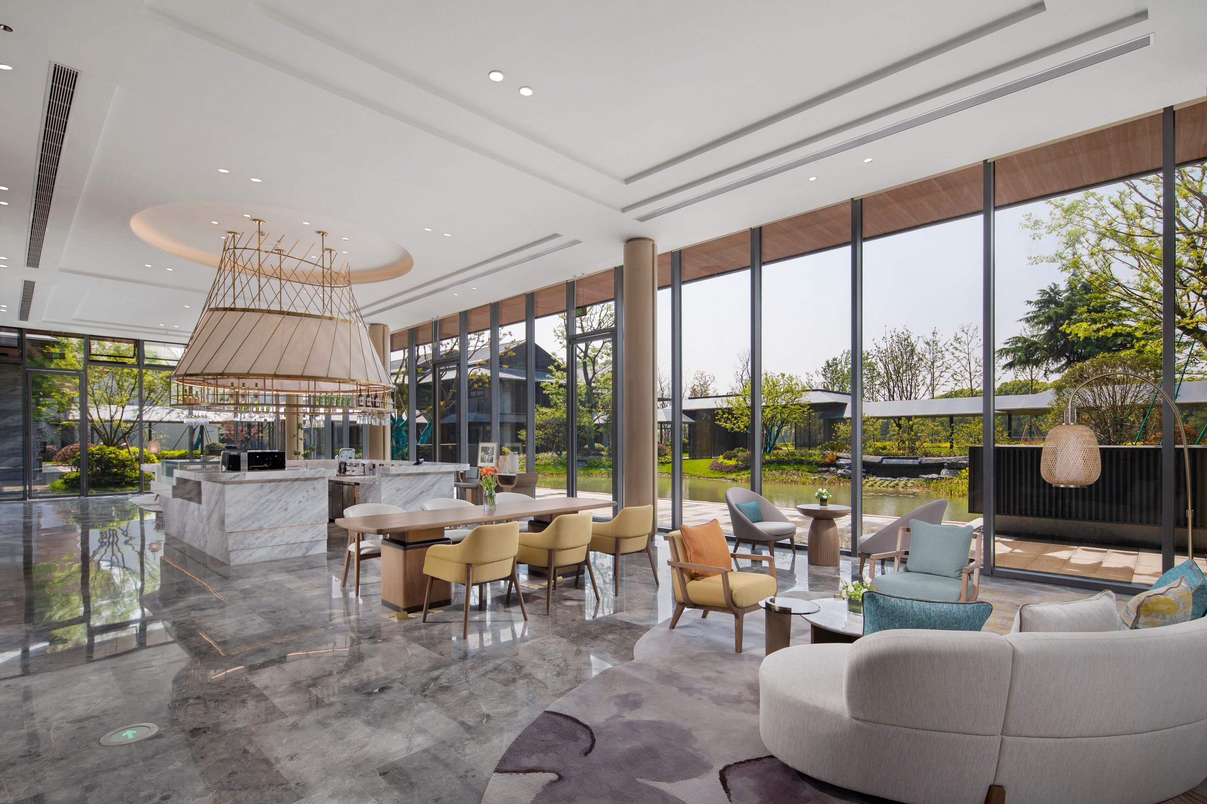 A spacious, modern interior with a marble floor, a central island with a sink, and a seating area with chairs and a sofa.