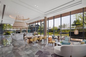 A spacious, modern interior with a marble floor, a central island with a sink, and a seating area with chairs and a sofa. - Holiday Inn Deqing Xinshi Ancient Town (Huzhou)