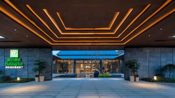 A modern hotel entrance with a geometric ceiling design and a large glass facade.