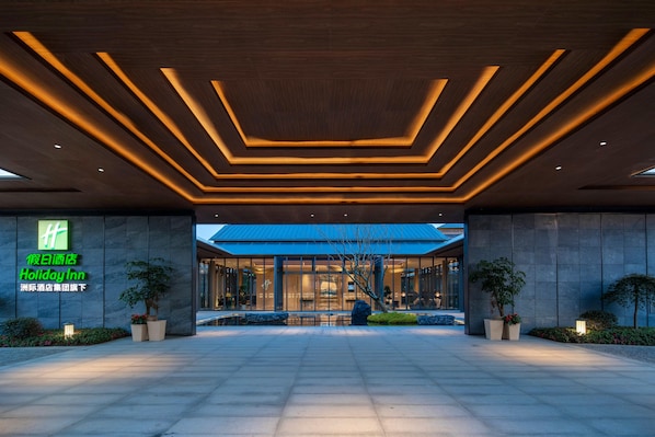 Ein moderner Hotel-Eingang mit geometrischem Deckenstil und einer großen Glasfassade.