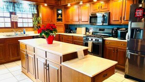 A kitchen with wooden cabinets, a central island, a stove, a microwave, and a refrigerator. - Lazy Bear Cabin Pet Friendly-Handicap Accessible (Frewsburg)