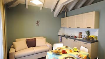 A cozy living room with a sofa and a dining table set with food and drinks.