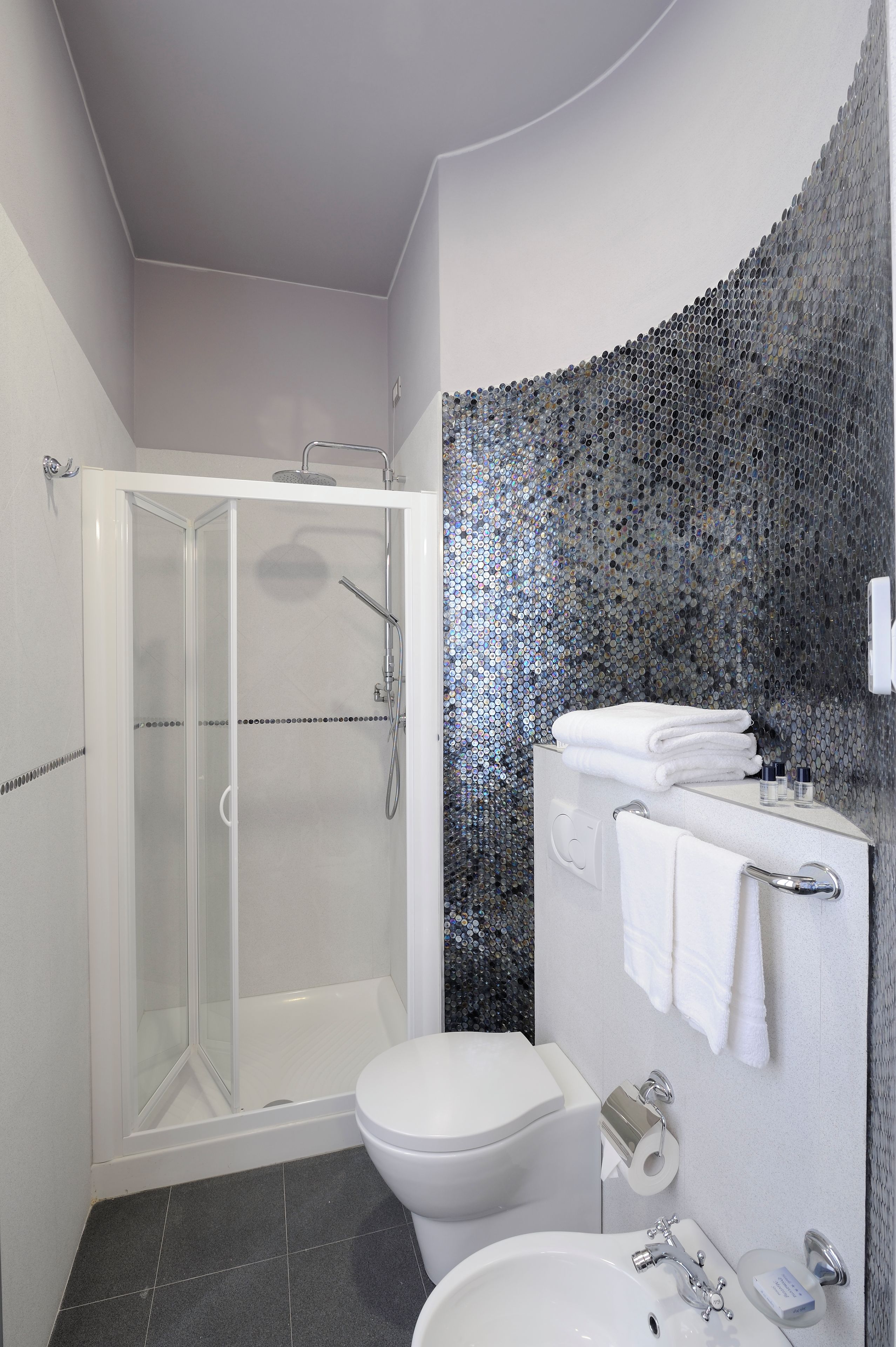 A modern bathroom with a glass-enclosed shower, a white toilet, and a sink with a mirror.