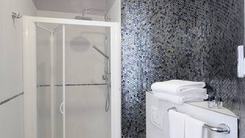 A modern bathroom with a glass-enclosed shower, a white toilet, and a sink with a mirror.