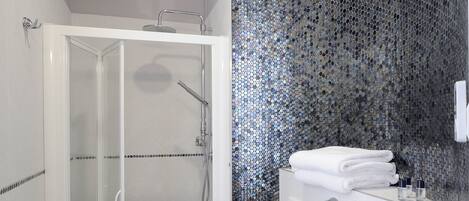 Un baño moderno con ducha envuelta en vidrio, inodoro blanco y lavamanos con espejo.