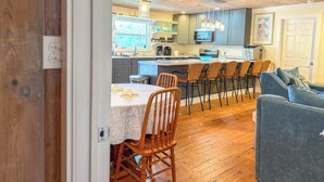 A kitchen with a bar area, wooden flooring, and a dining table with chairs. - Pet Friendly Sleeps 9 Golf Cart Hot Tub - Weekly Discounts (St.Geroge Island)
