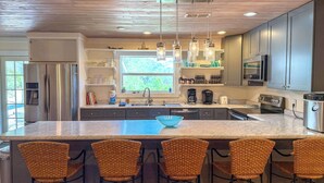 A modern kitchen with a large island, bar stools, stainless steel appliances, and pendant lighting. - Pet Friendly Sleeps 9 Golf Cart Hot Tub - Weekly Discounts (St.Geroge Island)