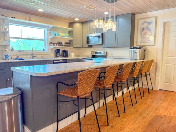 A modern kitchen with a central island, bar stools, and pendant lighting.