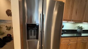 A stainless steel refrigerator with a water dispenser, wooden cabinets, and a tiled floor in a kitchen. - Luxury 3BR, 4BA Oasis: Beach is 2 blocks away, Indoor Pool, sleeps 8! Waterfront (Ocean City)
