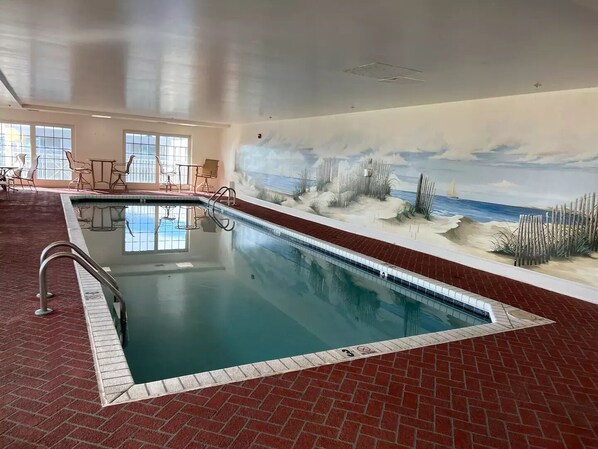 An indoor swimming pool with a mural of a beach scene on the wall.