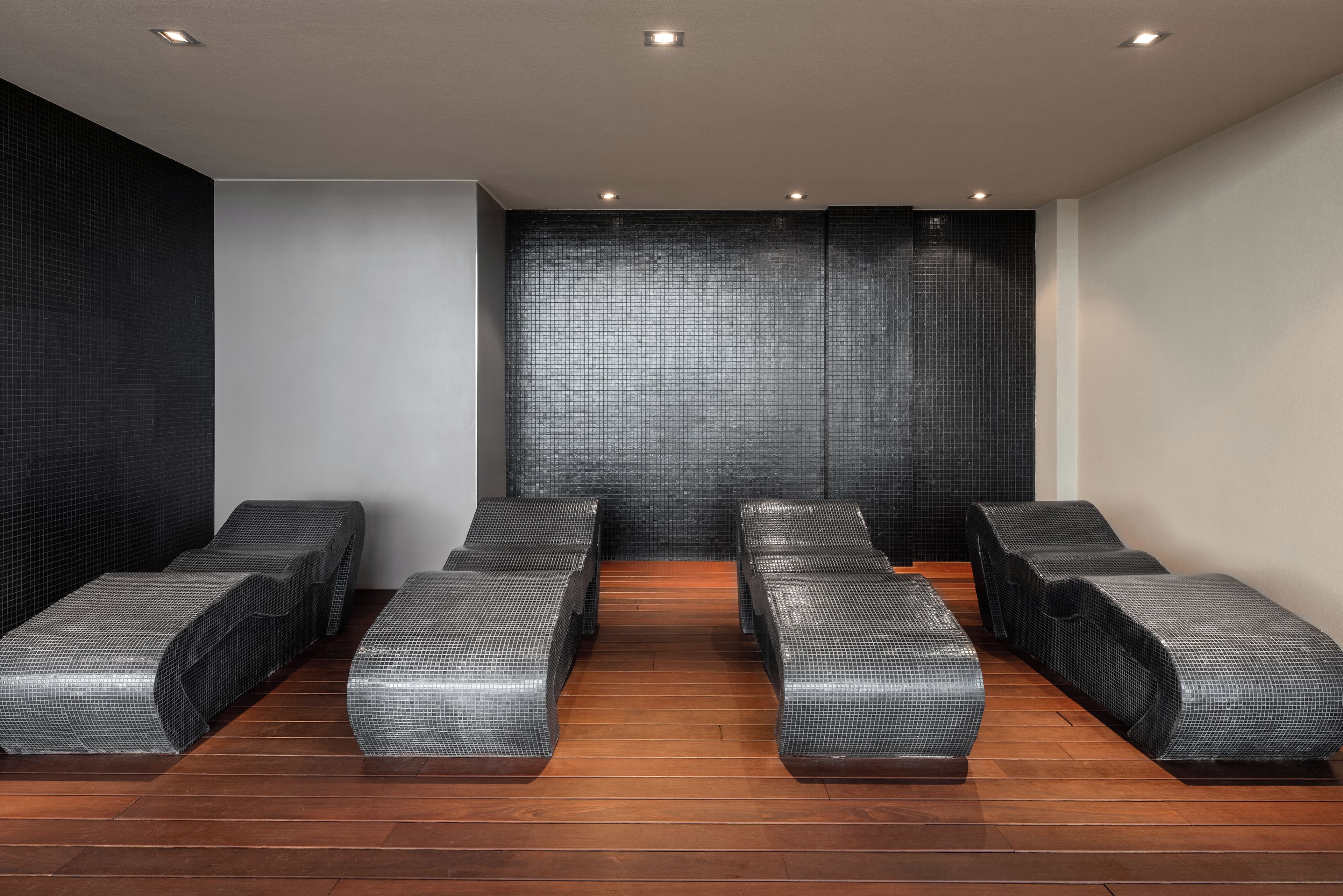 Un cuarto de spa con seis bancos acolchados negros dispuestos en dos filas.