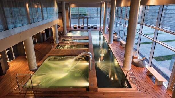 A spa area with multiple hot tubs and seating areas, large windows, and a wooden deck. - Valbusenda Hotel Bodega and Spa (Toro)