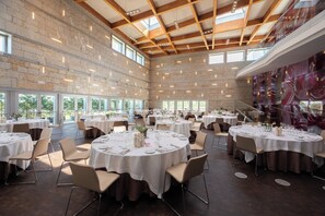 A spacious hall with multiple round tables set for dining, large windows allowing natural light, and a high ceiling with exposed beams. - Valbusenda Hotel Bodega and Spa (Toro)