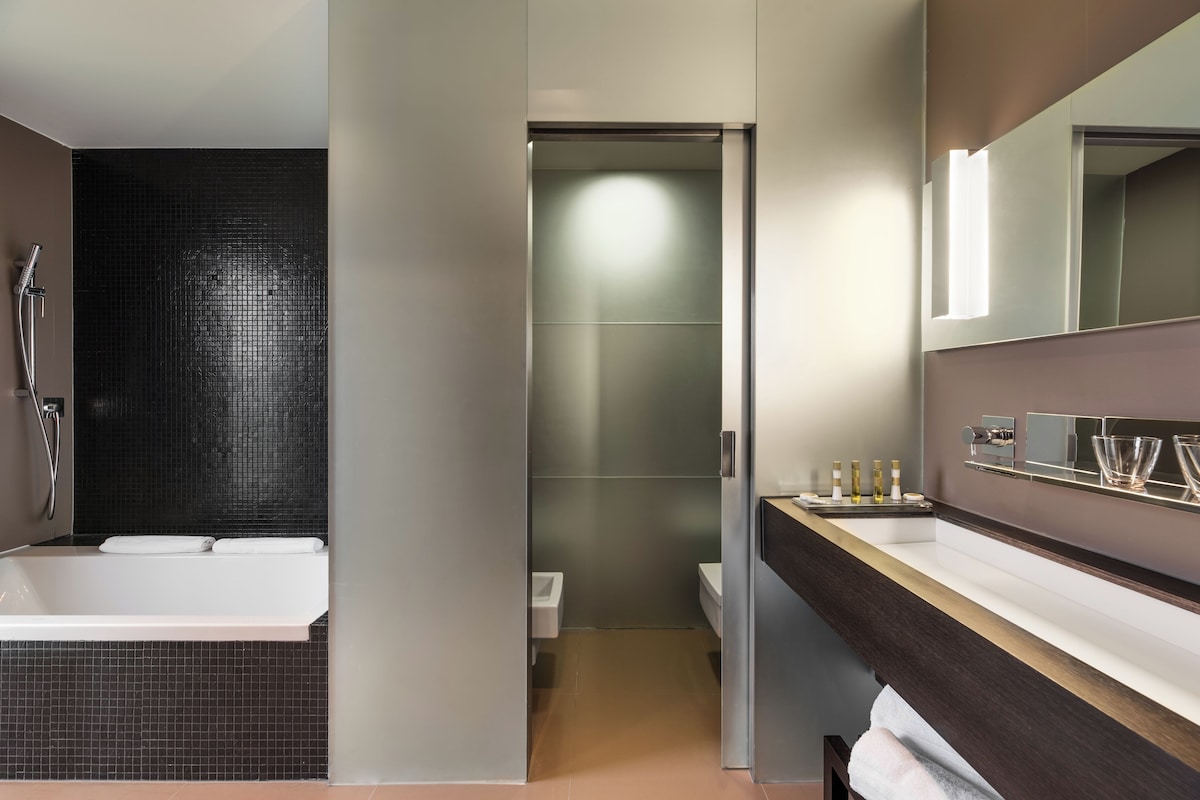 A modern bathroom with a bathtub, a shower, and a toilet.