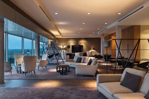 A modern interior with a large seating area, a dining table, and a view through large windows.