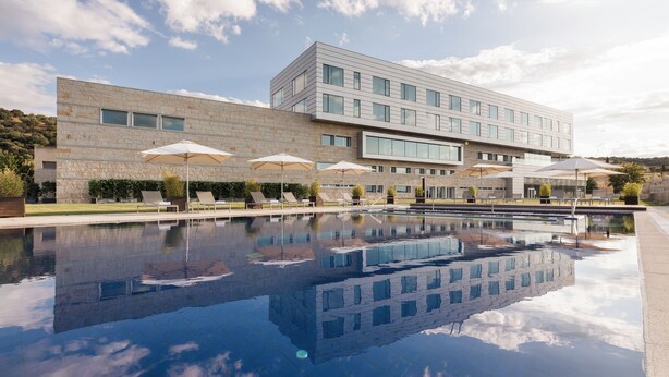 A modern building with a swimming pool, outdoor seating, and umbrellas. - Valbusenda Hotel Bodega and Spa (Toro)