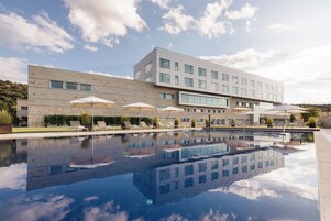 Un edificio moderno con piscina, asientos exteriores y sombrillas.