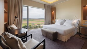 A hotel room with a large bed, a desk, a chair, and a view of the countryside. - Valbusenda Hotel Bodega and Spa (Toro)