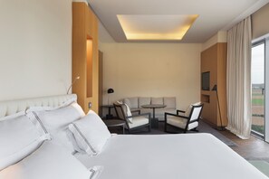 A hotel room with a large bed, a sofa, a small table, and chairs. There is a TV on the wall and a window with curtains. - Valbusenda Hotel Bodega and Spa (Toro)